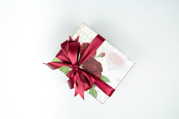 beautiful gift box tied with a ribbon with a red bow on a white background. A gift for a girl on a holiday