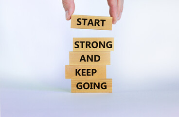 Start strong and keep going symbol. Concept words 'Start strong and keep going' on wooden blocks on a beautiful white background. Businessman hand. Business, motivational and start strong concept.