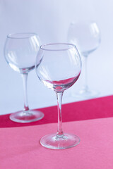Empty wine glasses on white, rose, red paper background