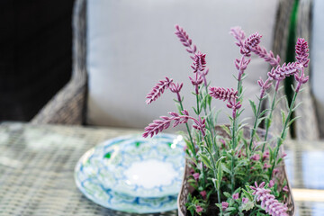 Artificial flowers on the dining table against the background of plates. Home decoration with plastic plants. Foreground