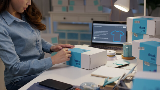 Young attractive beautiful hipster asia female packing product small business parcel order online retail store for delivery to customer. SME owner work preparing dropshipping box at home office.