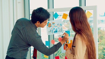 Business people work on project planning board in office and having conversation with coworker...