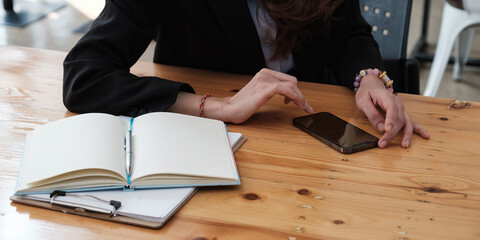 Closeup of business woman hand using mobile smart phone and reading message via application. Woman with a finger on the screen using a mobile phone in the office.
