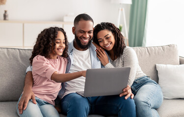 Happy african american family using laptop in living room
