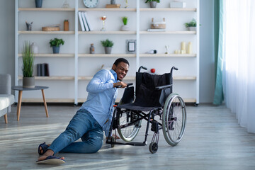 Young black man with disability lying on floor after falling down from wheelchair at home