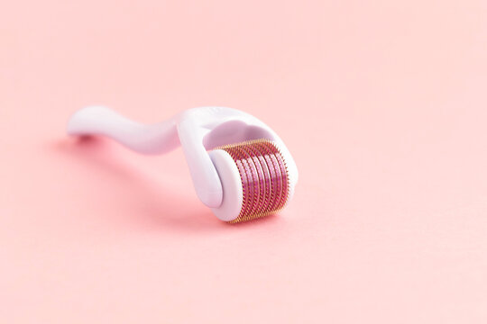 dermaroller, mesoroller, microneedling. cosmetic instrument with micro needles on pink background for skin care of face, neck, hands, fight against cellulite. closeup