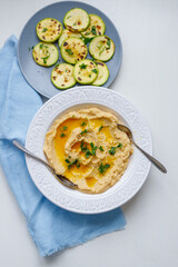 Top view of a plate of healthy homemade creamy hummus on a gray background zucchini and fresh bread for lunch
