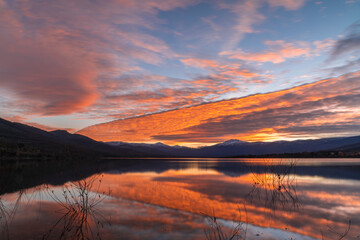 Fototapeta premium Atardecer en el lago con las montañas nevadas al fondo