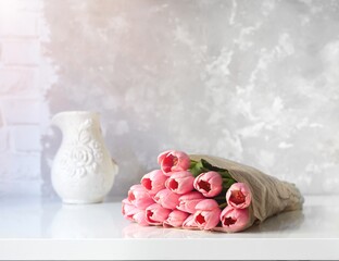 Bouquet of fresh pink tulips on white table. Copy space for text.