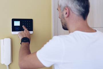 Man pressing buttons on control panel for disarming smart home system. Security alarm system.