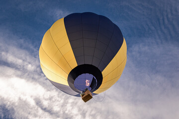 Obraz premium Die Flamme des Heißluftballons läßt ihn von unten gesehen zu den Wolken in den Himmel steigen