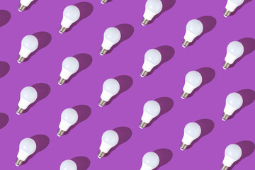 Glowing light bulbs against light purple background, flat lay pattern, minimal concept