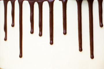 Chocolate drips on the background of white cream