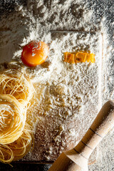 Freshly cooked pasta is lying on a dark surface dusted with flour. Italian pasta. Tagliatelle. Raw pasta. Italian pasta recipe. Top view, copy space
