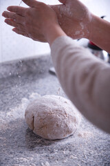 Woman's hands preparing homemade bread dough in a kitchen.
