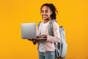Black girl wearing backpack standing with laptop at studio