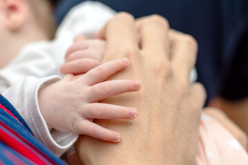 Die Hand eines neugeborenen Babys liegt zufrieden auf dem Handrücken der Mutter