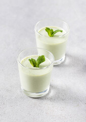 Jelly cream green mint in a glass on a light gray background
