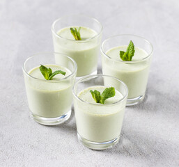 Vegan dessert Panna Cotta green mint in a glass on a light gray background