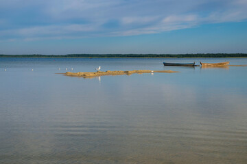 Quiet morning on the lake. Wooden boats, sand dunes, seagulls. Copy space.