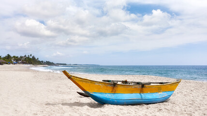 Small fishing boat on an empty tropical beach, Sri Lanka.