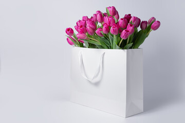 pink tulip flowers in a cardboard bag on white background