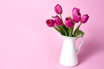 tulip flowers in a jug on pink background
