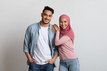 Modern muslim couple man and woman in hijab posing on gray background