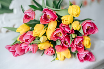 Fresh spring yellow and pink tulips bouquet on white wood table background with copy space for text. Love, easter, International Women day, Mother day and Happy Valentine day concept