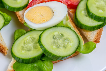 Fried white bread toasts with vegetable and egg slices on a plate