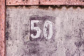 house number 50. pink, lilac old shabby wall. cracks and peeling paint.