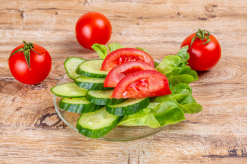 Vegetable slicing of cucumbers and tomatoes on a plate on a wooden background