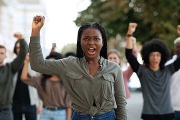 Black woman raising fist up, leading international group of demonstrators