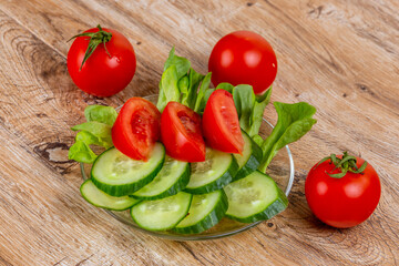 Vegetable slicing of cucumbers and tomatoes on a plate on a wooden background