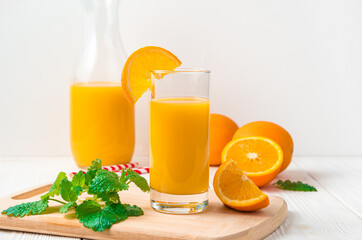 Orange juice in a glass on the background of fresh oranges.