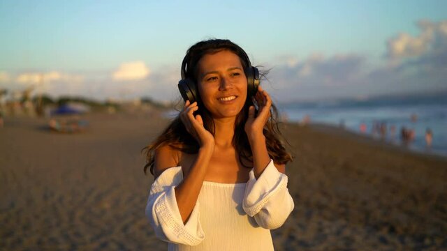 Happy, beautiful woman listen to music on the beach