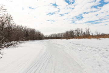 The winter road is laid on the ice of a frozen river away populated areas. Sunny frosty winter day.
