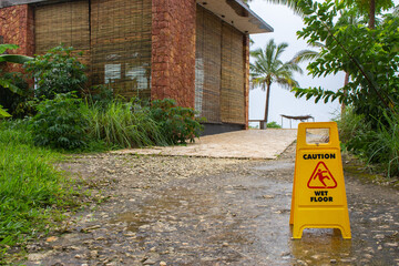 Warning yellow sign with text Wet floor and Caution. Outdoor caution sign in hotel garden. Safety...