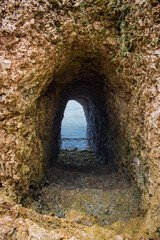 Cave with entrance to the sea. Natural tunnel in cave. Passage in rocks. Natural staircase in ocean cave.