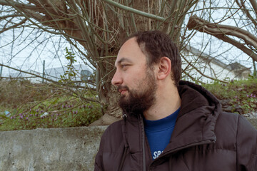 profile of a attractive businessman looking left in front of a tree and wall