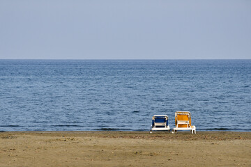 Fototapeta na wymiar Two beach chairs on the shore of the Mediterranean Sea in Larnaca, Cyprus