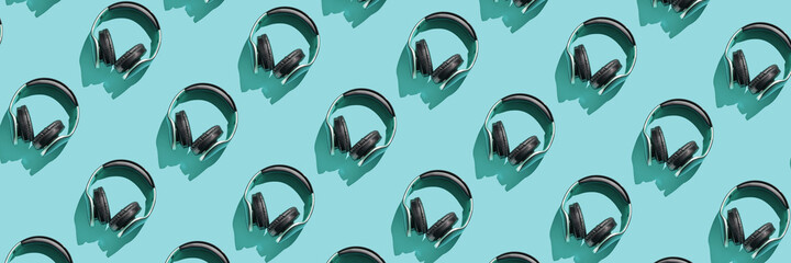 Many same headphones on blue bright background. Modern music concept. Top view repeat layout. Headset trend wallpaper. Flatlay. Technology hipster accessory
