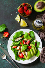Healthy food, diet lunch menu concept, ketogenic diet and paleodiet. Summer salad with strawberries, grilled chicken and avocado on a stone table. Top view flat lay.