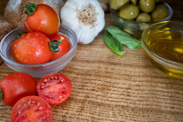Basic ingredients of the Mediterranean diet on the kitchen table: tomato, garlic, basil and extra virgin olive oil with copy space for message