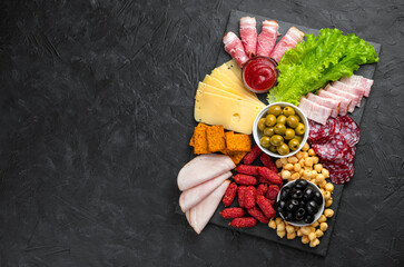 Slate board with slicing of different sausages and cheese. Charcuterie board. Meat delicacies.