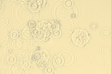 Fototapeta na wymiar Water background. Yellow water texture, disturbed surface with rings and ripple. Spa concept background. Flat lay, top view, copy space, copy-space.