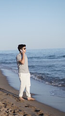 young boy using cell phone on the beach