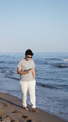 young boy using cell phone on the beach