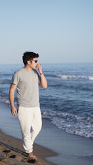 a young caucasian man walking on the beach in summer relaxing