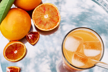 Summer orange cocktail. Fresh healthy citrus juce with ice on steel tray top view. Ripe bio citrus fuits in background. Organic Sicilian oranges.